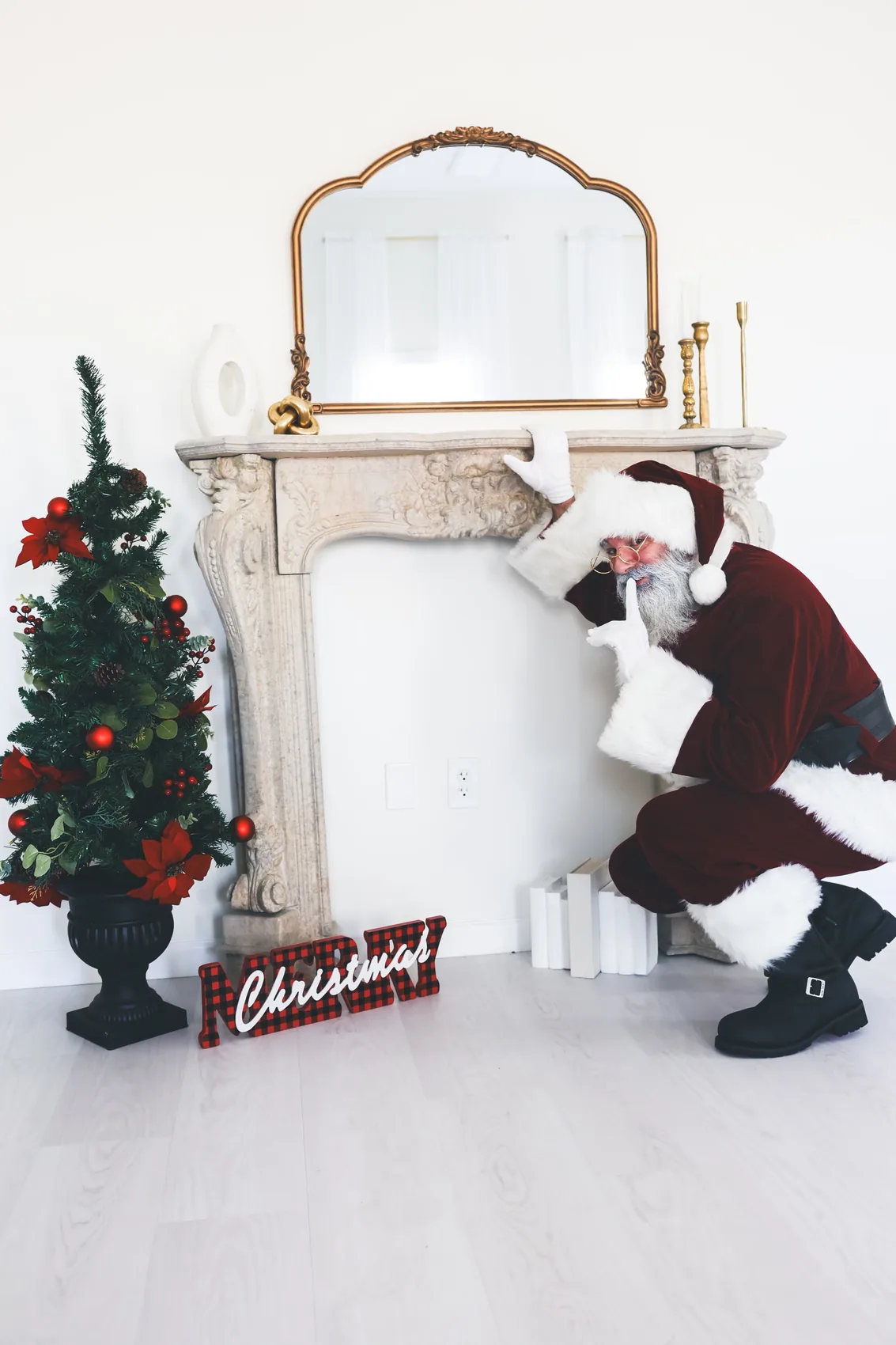 Santa playfully gestures for quiet while sneaking near a festive fireplace